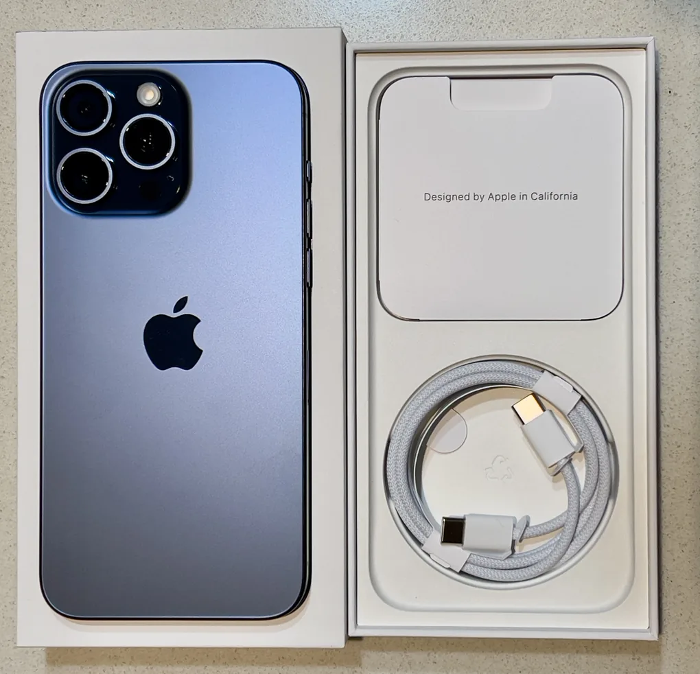 Mặt lưng iPhone 15 Pro Max màu Titan Xanh đặt trong hộp, cạnh cáp sạc USB-C
