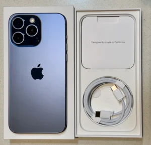 Mặt lưng iPhone 15 Pro Max màu Titan Xanh đặt trong hộp, cạnh cáp sạc USB-C