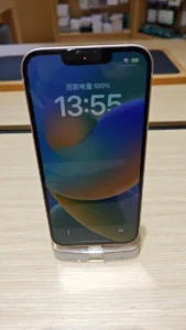 Mặt trước iPhone 13 màu Hồng dựng trên giá đỡ trong suốt, màn hình khoá bật sáng